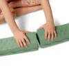 Dziecko łączy zielone, pofalowane belki równoważne zestawu Balance & Groove Set SOFT COLORS B. toys, tworząc własną ścieżkę sensoryczną