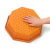 Dłoń dziecka dotyka pomarańczowego kamienia sensorycznego Balance & Groove Set SOFT COLORS o nachylonej powierzchni i trójkątnych wypustkach