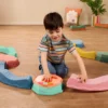 Chłopiec układa elementy muzycznej ścieżki sensorycznej Balance & Groove Set SOFT COLORS B. toys i łączy belkę z modułem muzycznym