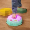 Zbliżenie na stopę dziecka na podświetlonym module muzycznym Balance & Groove Set SOFT COLORS B. toys, obok nachylone kamienie sensoryczne z wypustkami