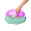Dziecko naciska przycisk na podświetlonym module muzycznym Balance & Groove Set SOFT COLORS B. toys, wybierając jedną z trzech gier